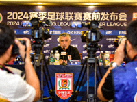 足球赛前新闻发布会现场，主教练面对媒体镜头发表讲话